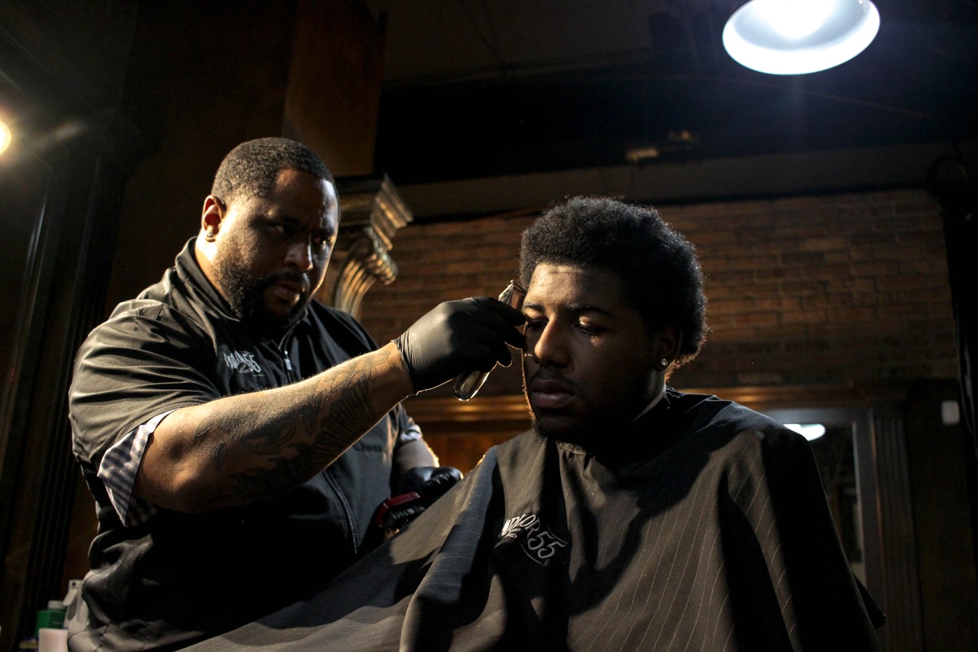 A barber carefully shaping a client’s haircut in a neighborhood barbershop